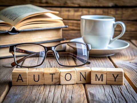 Wooden letter blocks with autonomy concept spelled out on a rustic wooden table surrounded by vintage glasses and an open book, conveying independence.