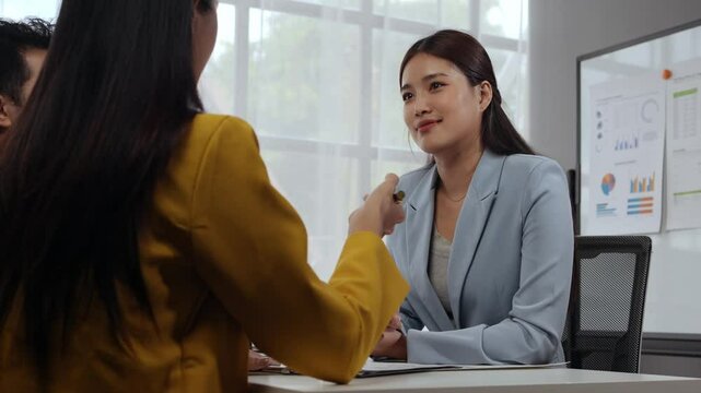 Businesswomen engaging in a meeting, negotiating a contract, and signing the agreement in a professional office setting