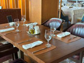 Cozy restaurant interior with elegantly set table, ready for guests. the warmth of the wooden accents and green plants create a welcoming atmosphere.