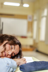 Portrait of young female student falling asleep at desk during a class. Bad student. Doesn't like going to school. Doesn't pay attention to teacher's explanations.