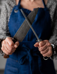 Big Kitchen Knife And Sharpener In Female Hands Are In Close-Up View