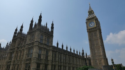 Obraz premium Sunny summer day in London, capturing the iconic Big Ben with clear skies. Showcasing the historic landmark's intricate architecture and its prominent place in the city's skyline.