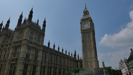 Obraz premium Sunny summer day in London, capturing the iconic Big Ben with clear skies. Showcasing the historic landmark's intricate architecture and its prominent place in the city's skyline.