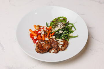 A hearty lunch with meat and vegetables on a large white plate.