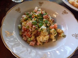  Olivier salad in a white plate with golden patterns. Traditional Russian dish for Christmas and New Year.  