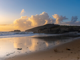 Atardecer en una playa con acantilados y montañas que entran en el mar
