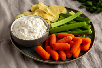 Homemade Carmelized Onion Dip with Baby Carrots, Chips and Celery, side view.