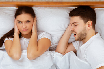 Snorting Problem. Angry Wife Covering Ears Trying To Sleep Near Snoring Husband In Bed At Home....