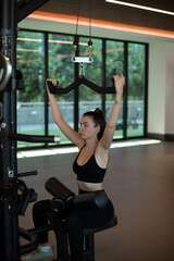 lat pulldown a woman exercising in the gym on a vertical pull machine, pumping up arm muscles on a machine