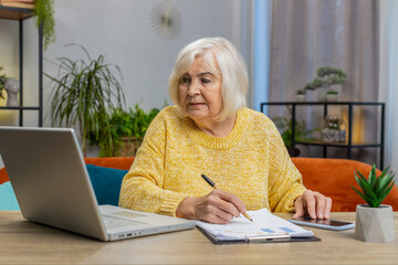 Senior old woman accounting payments calculating monthly expenses bank bills analyzing paperwork at...