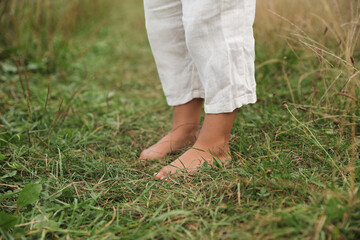 Little child standing barefoot on green grass outdoors, closeup. Enjoying nature