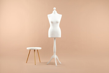 Female mannequin and stool on beige background
