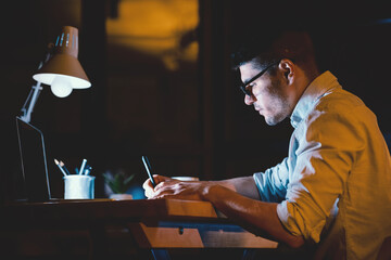 Career Opportunities. Millennial Guy Working At Laptop Late At Night Sitting In Modern Office. Low Light