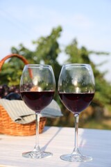 Tasty wine in glasses on white wooden table outdoors