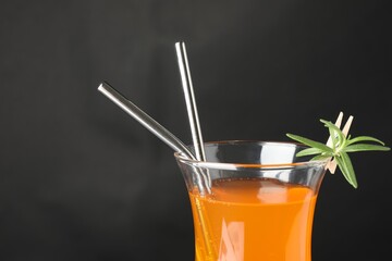 Tasty refreshing drink with straws in glass on grey background, closeup