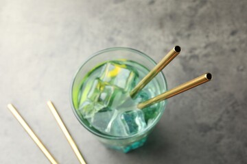 Tasty refreshing drink with straws in glass on grey table, closeup