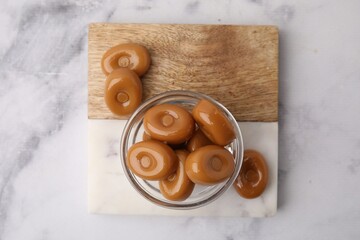 Tasty hard toffee candies on white marble table, top view