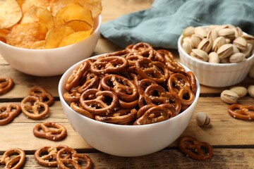 Delicious pretzel crackers and other snacks on wooden table, closeup