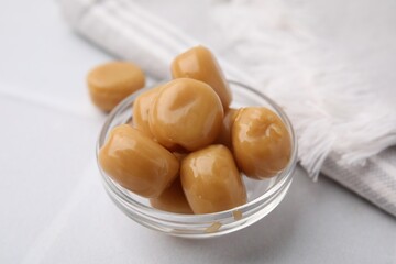 Tasty hard toffee candies in glass jar on light table, closeup