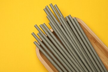 Bamboo drinking straws on yellow background, top view