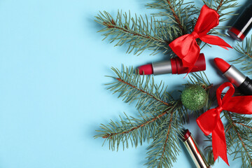 Lipsticks and Christmas decor on light blue background, flat lay. Space for text