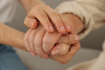 Caregiver supporting senior woman at home, closeup