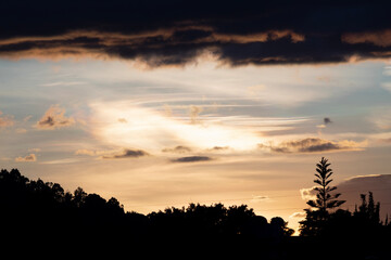 stunning orange and blue sunset with mountains and trees silhouette