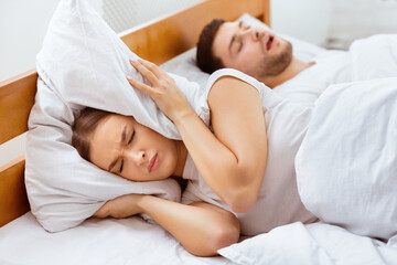 Snoring. Unhappy Girlfriend Trying To Sleep Near Snorting Boyfriend In Bed Indoor. Selective Focus