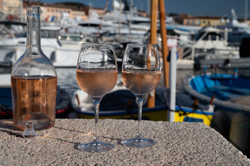Glasses of cold rose Cote de Provence wine in old fisherman boats and yacht harbour in Saint-Tropez, summer vacation on French Riviera in Provence, France