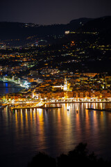 Obraz premium Night view on French Riviera, lights of Menton old city and marina on blue Mediterranean Sea near French-Italian border, Monaco, Monte-Carlo, travel destination, panoramic view