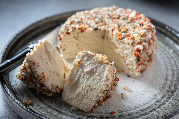 French cheese collection, fresh white soft goat cheese with aromatic herbs, garlic, parsley and red peppers close up