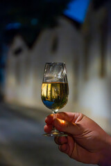 Hand with sherry wine glass with fino and old bogedas jerez wine cellars on background in Jerez de la Frontera, wine glasses outdoor, cityview, Andalusia, Spain