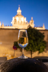 Sherry wine glasses with fino and old bogedas jerez wine cellars on background in Jerez de la Frontera, wine glasses outdoor, cityview, Andalusia, Spain