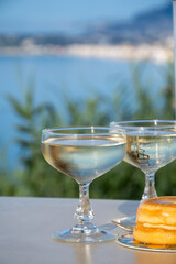 Sparkling wine, cava or champagne in two coupe glasses on table with view on blue sea, Menton and Monte-Carlo, French Riviera, France is summer