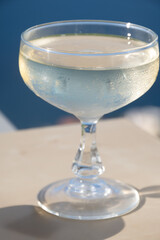 Cold sparkling wine, cava or champagne in two coupe glasses on table with blue sea water view