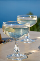 Cold sparkling wine, cava or champagne in two coupe glasses on table with blue sea water view, French Riviera is summer, France
