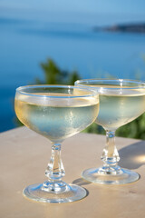 Sparkling wine, cava or champagne in two coupe glasses on table with view on blue sea, Menton and Monte-Carlo, French Riviera, France is summer