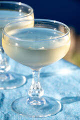 Cold sparkling wine, cava or champagne in two coupe glasses on table with blue sea water view