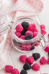 Sweet jelly candies in jar on white table.