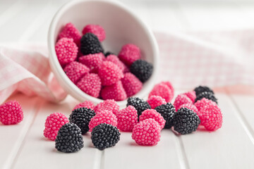 Sweet jelly candies in bowl on white table.