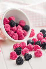 Sweet jelly candies in bowl on white table.