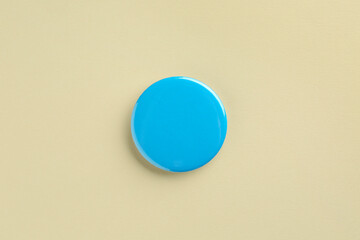 Blue button badge on beige background, top view. Mockup for design