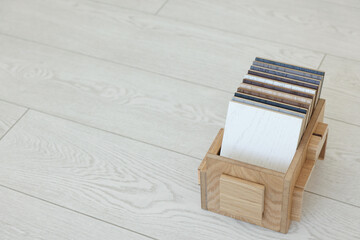 Different samples of wooden flooring in crate indoors, space for text