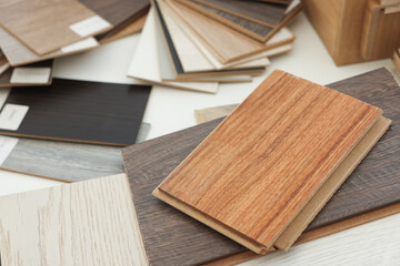 Different samples of wooden flooring on white table, closeup