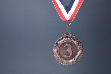 Bronze medal with striped ribbon on grey background, space for text