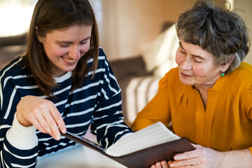 Fototapeta premium Old woman with her granddaughter look at family photos.