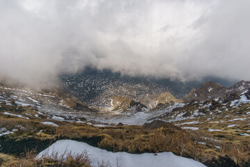 Volcanic landscape of Mount Etna with black lava and yellow grass on a cloudy winter day, Catania, Sicily, Italy