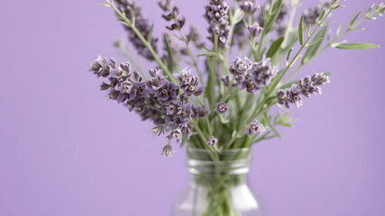 Naklejka premium on a purple background with a transparent vase with lavender flowers