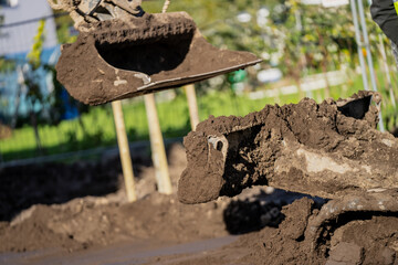 Industrial mini excavator close up of construction bucket and excavator blade in very dirty earth moving project before constructing the building and moving earth around