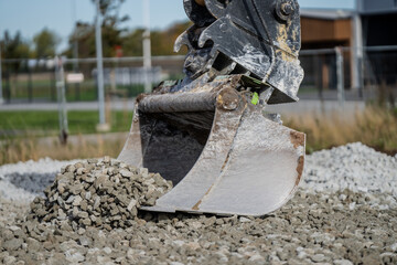 Excavator steel bucket working hard on lifting gravel for preparation of construction building